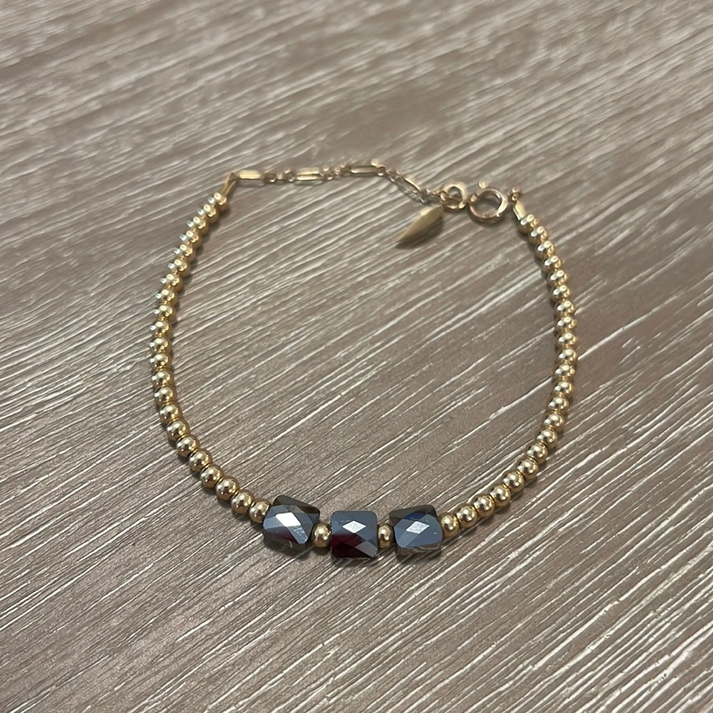 Gold beaded bracelet with black stone accents